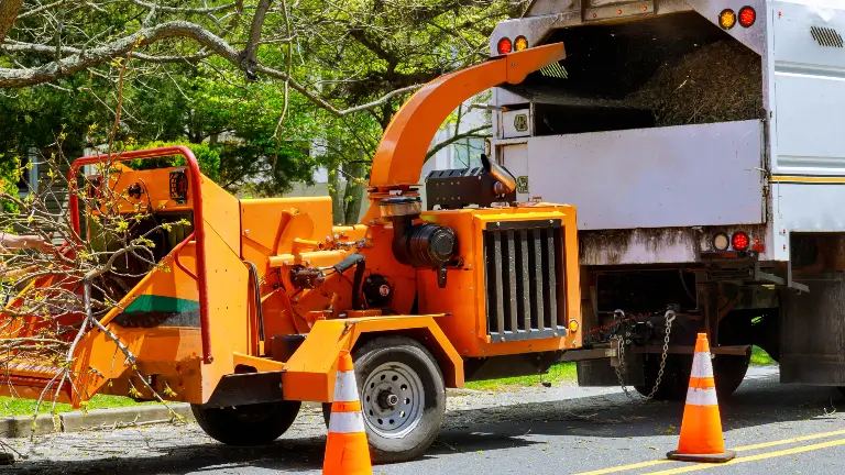 Wood chipper loaded cut green tree branches in urban neighborhood