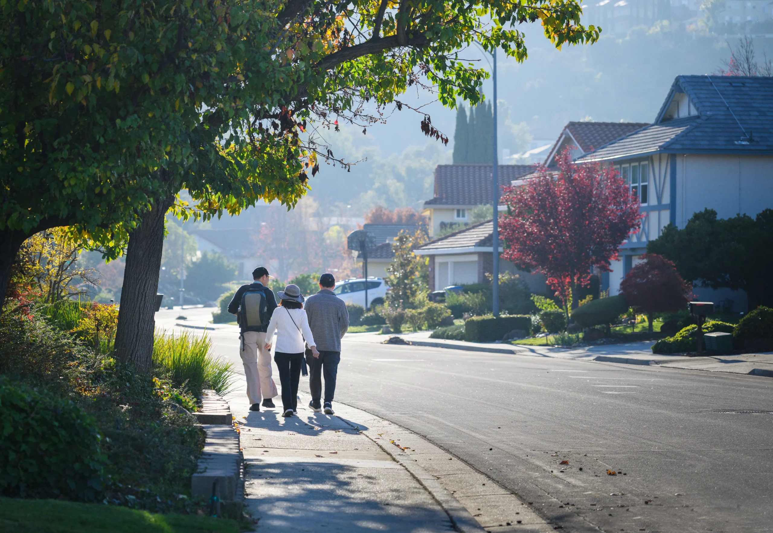 A family walking down a sidewalk in a San Jose CA neighborhood.